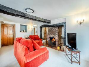 a living room with two red chairs and a fireplace at Hazel Cottage in Tolpuddle