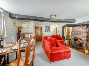 a living room with a red couch and a fireplace at Hazel Cottage in Tolpuddle