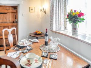 a dining room table with a bottle of wine and glasses at Hazel Cottage in Tolpuddle