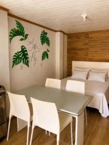 a bedroom with a bed and a table and chairs at Pousada Cristais do Rosa in Imbituba