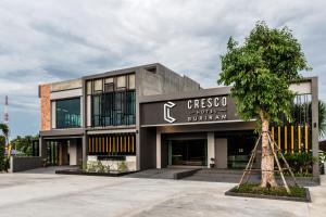 武里南Cresco Hotel Buriram的前面有一棵树的建筑物