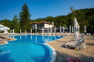 a large swimming pool with lounge chairs and umbrellas at Ostrova Holiday Village in Beli Osŭm