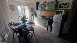 a kitchen with a table with chairs and a white refrigerator at Maison le palmier in Troarn