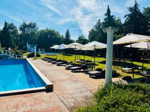 a pool with chairs and umbrellas and a group of tables and chairs at Bungalow Park Balatonboglár in Balatonboglár