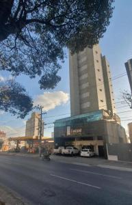 a large building with cars parked in front of it at Via Contorno Hotel in Belo Horizonte