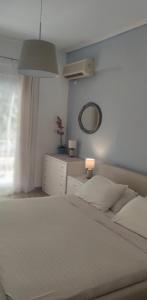 a bedroom with a white bed and a mirror at Loutraki by the sea in Loutraki