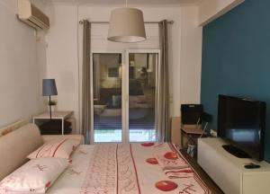 a bedroom with a bed and a television and a window at Loutraki by the sea in Loutraki