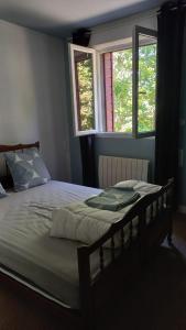 a large bed in a bedroom with two windows at La Bouee, entre Manche et Seine in Saint-Nicolas-de-la-Haie
