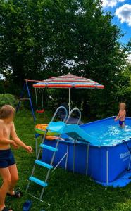 two children playing in a pool with an umbrella at Familien FEWO Spielzimmer Balkon nahe Freizeitpark Plohn DZ eig Bad Küche gratis Kaffee Sitzecke Gemeinschaftspool im Garten Frühstückskorb auf Anfrage in Auerbach