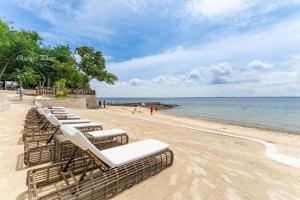 a row of chaise lounge chairs on a beach at Mactan Newtown Condo with Pool access in Mactan