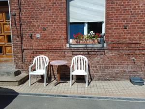 two chairs and a table in front of a brick building at A la ferme chez Christian in Escaudoeuvres