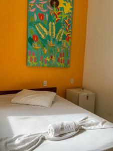 a bed in a room with a painting on the wall at Pico das Praias Suites in Itacaré