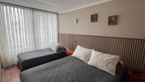 a hotel room with two beds and a window at Departamentos Alpro Cavancha Vista a la Playa in Iquique