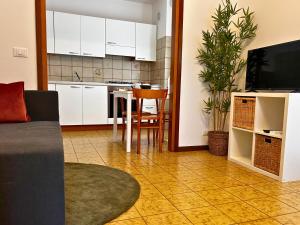 a living room with a table and a kitchen with white cabinets at Reunia apartments in Ragogna