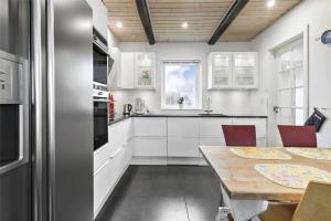 a kitchen with white cabinets and a wooden table at 12231-Sjaellands-Odde-Rogerivej-2 in Havnebyen
