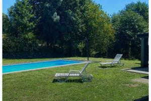 two lounge chairs sitting in the grass near a swimming pool at Geres - Gateway House - Terras de Bouro in Terras de Bouro