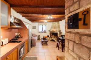 a kitchen and living room with a stone fireplace at Petalidi Olive Garden Stone House near the beach in Petalidi