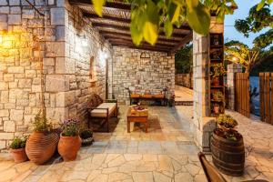 an outdoor patio with potted plants and a stone wall at Petalidi Olive Garden Stone House near the beach in Petalidi +40 photos