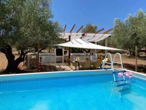 a large swimming pool with chairs and an umbrella at Bellissima Bell Tent - Romantic Glamping Retreat in Nature in Tortosa