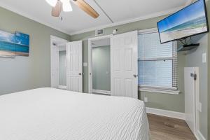 a bedroom with a white bed and a flat screen tv at Seventh-floor oceanfront condo with pool access ocean view & central AC in Fort Walton Beach