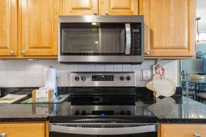a kitchen with a stove top oven with a microwave at Seventh-floor oceanfront condo with pool access ocean view & central AC in Fort Walton Beach