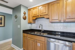 a kitchen with wooden cabinets and a sink at Seventh-floor oceanfront condo with pool access ocean view & central AC in Fort Walton Beach