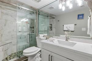a bathroom with a shower and a toilet and a sink at Seventh-floor oceanfront condo with pool access ocean view & central AC in Fort Walton Beach +23 photos