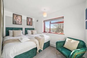 a bedroom with two beds and a green chair at Spacious 3BED Home in Rugby - Ideal for Groups in Clifton upon Dunsmore