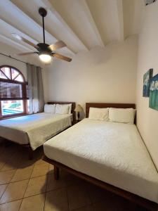 a bedroom with two beds and a ceiling fan at Bel Air/Sutton in San Juan del Sur +35 photos