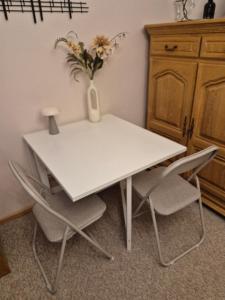 a white table with two chairs and a vase with flowers at Gastenverblijf Franz-Marc in Bad Bentheim +4 photos