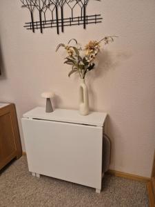 a white vase with flowers on top of a dresser at Gastenverblijf Franz-Marc in Bad Bentheim