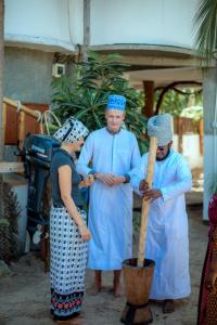 a group of three people in blue robes holding a bat at Peace House Zanzibar in Bwejuu