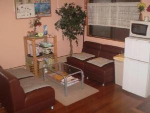 Sala de estar con 2 sofás y mesa en Hostel Hakuseiso, en Naha