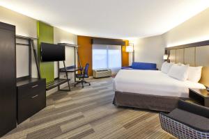 a hotel room with a bed and a flat screen tv at Holiday Inn Express & Suites Chicago-Midway Airport by IHG in Bedford Park