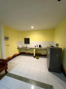 a kitchen with yellow walls and a white tile floor at Jano House in Ban Mae Nam