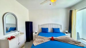 a bedroom with a blue bed and a mirror at Experience the Pool View Dream at Estrella Dominicus in Bayahibe