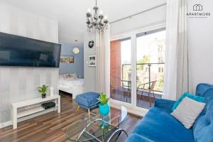a living room with a blue couch and a glass table at City Center - AURA by Apartmore in Gdańsk