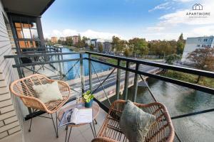 two chairs and a table on a balcony with a river at City Center - AURA by Apartmore in Gdańsk