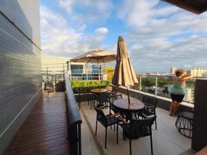 a woman taking a picture of a balcony with tables and umbrellas at PARK DEL PRADO - Conforto pertinho do mar in Cabedelo