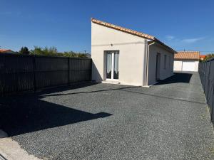 a white house with a fence and a driveway at Petit gîte a côté des plages in Triaize