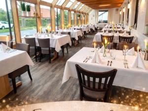a restaurant with white tables and chairs and windows at Hotel-Restaurant Krüger in Grafhorst