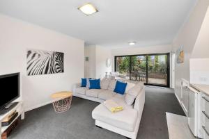 a living room with a white couch and a tv at BYO Linen - Aireys Delight in Aireys Inlet