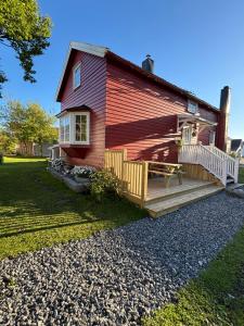 a red house with a porch and a deck at Gammel stua AS in Andøya