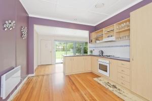 an empty kitchen with purple walls and wooden floors at Anderson in Apollo Bay