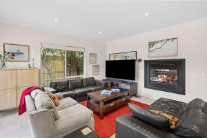 a living room with couches and a tv and a fireplace at Beach Living Bliss in Torquay