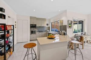 a kitchen with a island and two bar stools at Beach Living Bliss in Torquay +12 photos