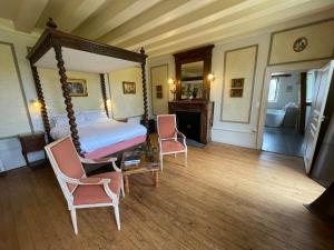 a bedroom with a canopy bed and two chairs at Château De La Coutancière in Brain-sur-Allonnes