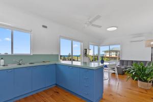 a kitchen with blue cabinets and a living room at Blue Surf - BYO Linen in Apollo Bay