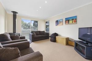 a living room with couches and a flat screen tv at Budget By The Bay in Apollo Bay