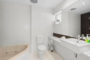 a white bathroom with a tub and a toilet and a sink at Bay View Motel - Sunrise in Lorne